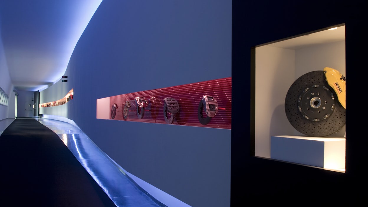 A corridor illuminated in blue with red display cabinets with five brakes on display.