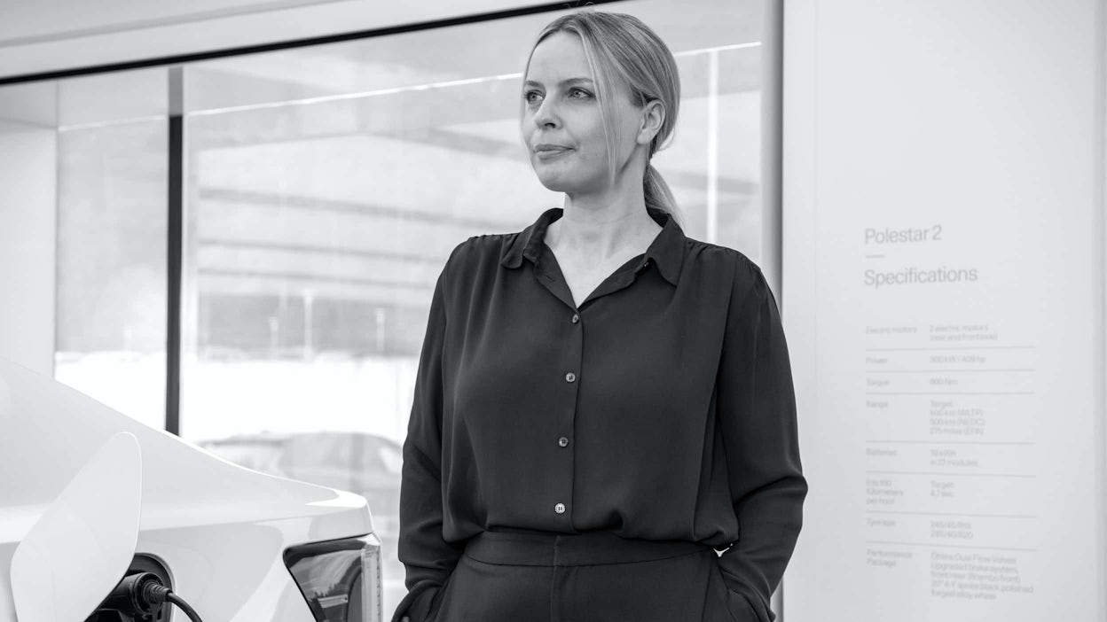 Fredrika Klarén standing next to a Polestar 2 wearing a black suit.