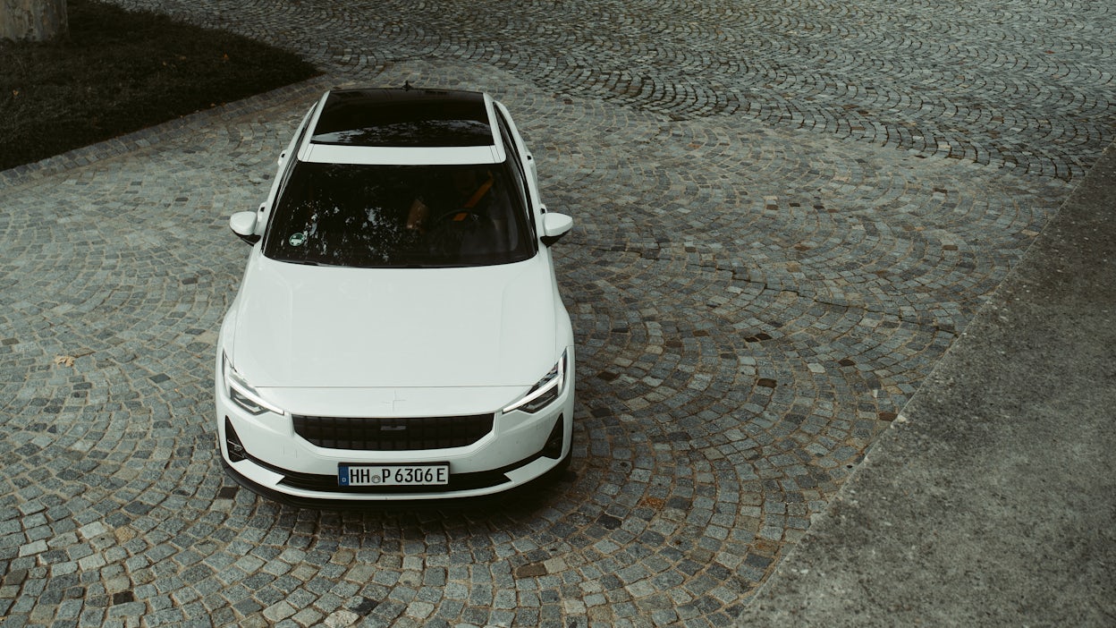 White Polestar 2 parked on a cobblestone driveway.