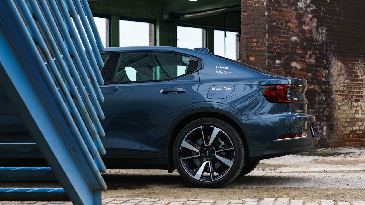 Side view of a blue Polestar 2 parked next to a light blue staircase.