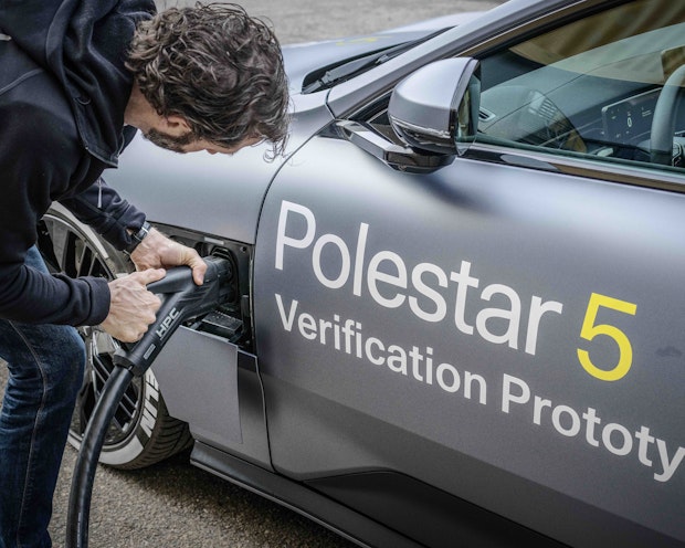 Een grijze elektrische auto Polestar 5 wordt ingeplugd voor stroom