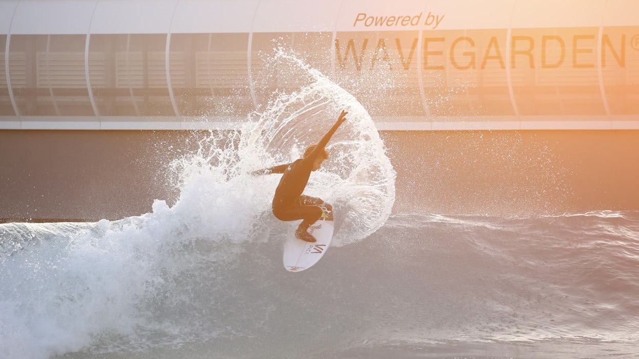 Surfer riding wave with building in background