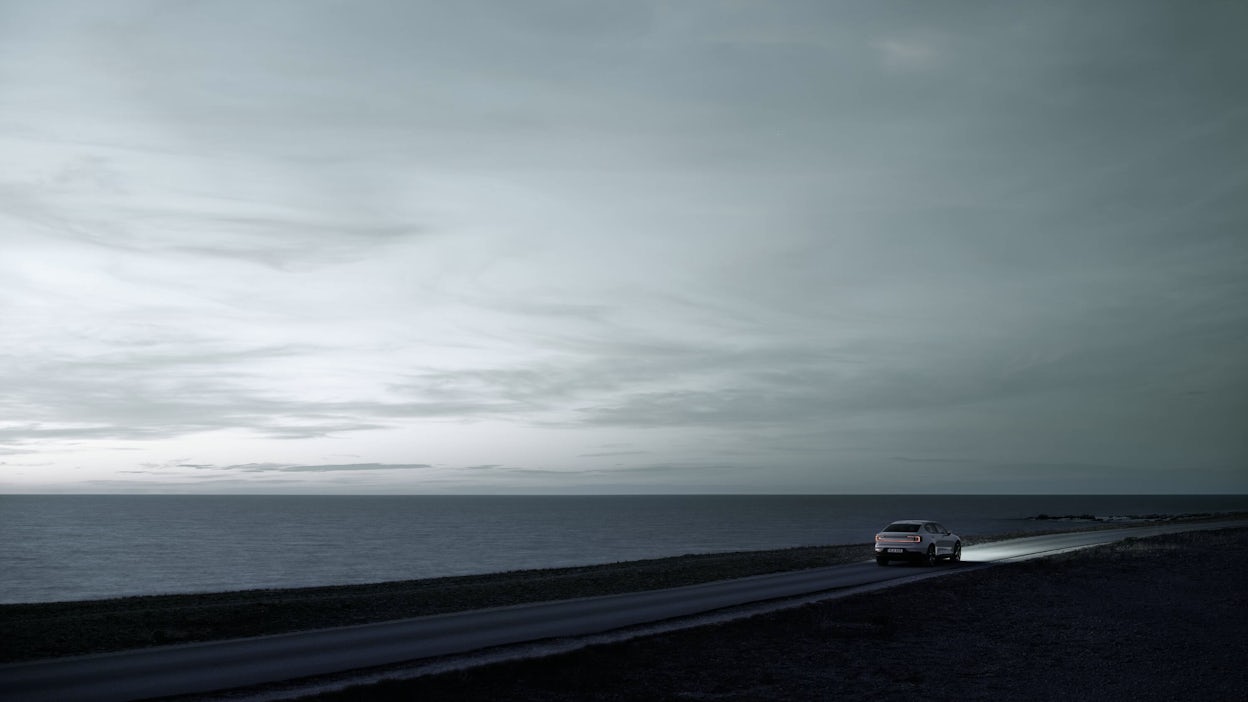 Polestar 2 driving down coastal road in fading light