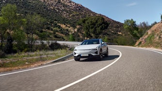 Polestar 3 in Snow color driving on a winding road in Spain, surrounded by trees and mountains