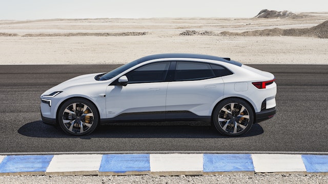 A white Polestar 4 electric SUV coupé is parked on a desert road next to a blue and white curb on a clear day.