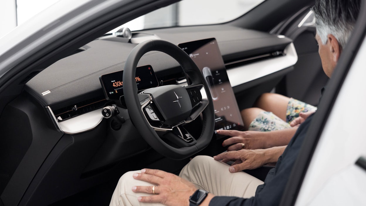 Inside a Polestar 3, where two people are looking at the steering wheel and display