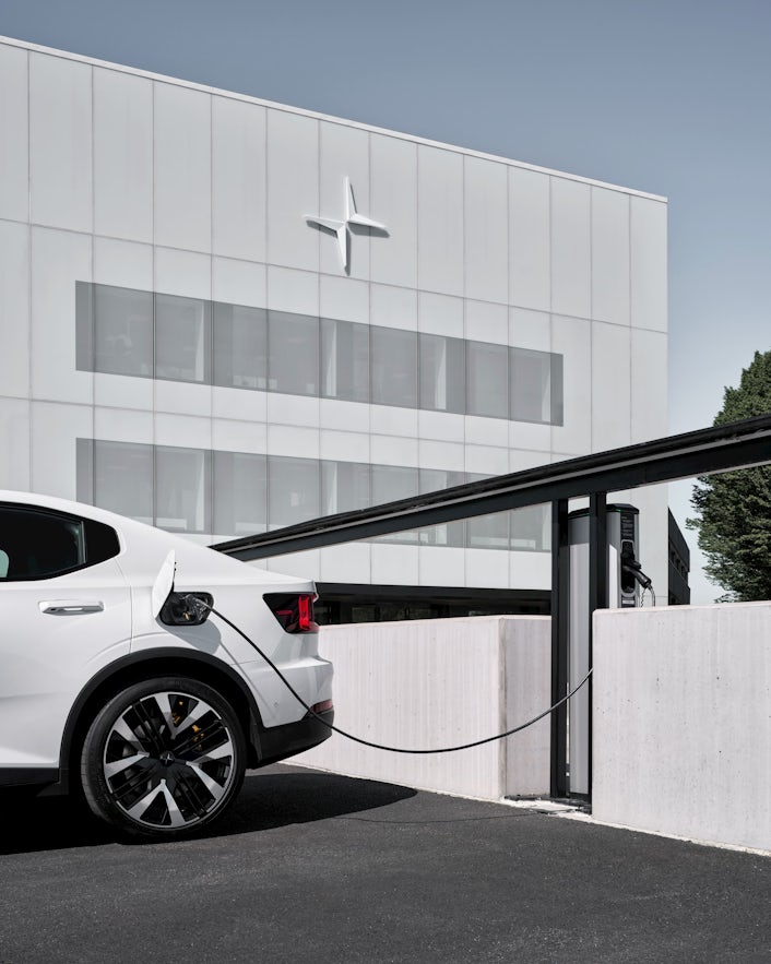 De witte elektrische auto Polestar 2 staat op te laden voor Polestar HQ