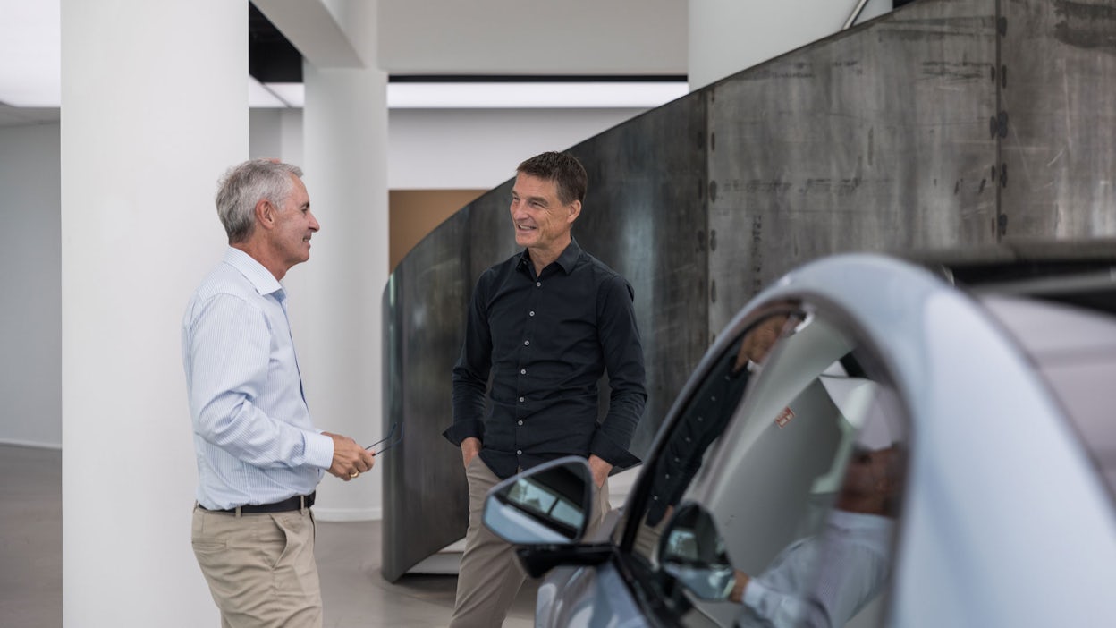 Thomas Ingenlath talking with a customer, with a part of a Polestar 4 visible in front of them