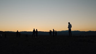 A group of people in the desert at sunset.