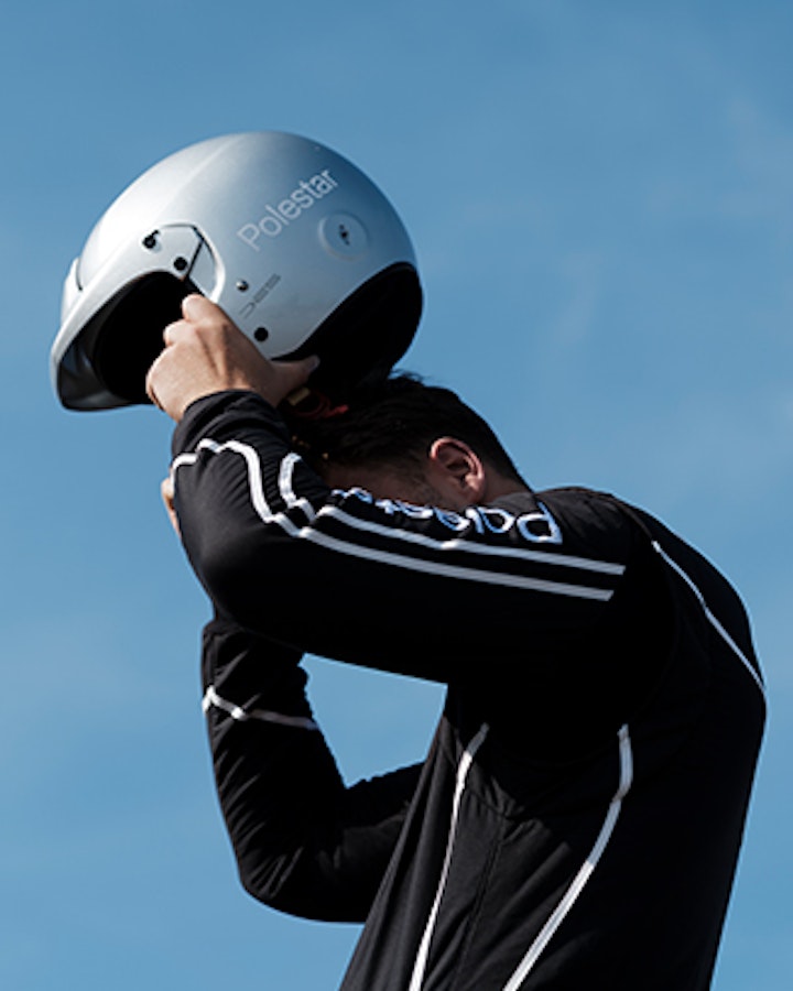 Race driver putting on helmet clear blue sky in the background