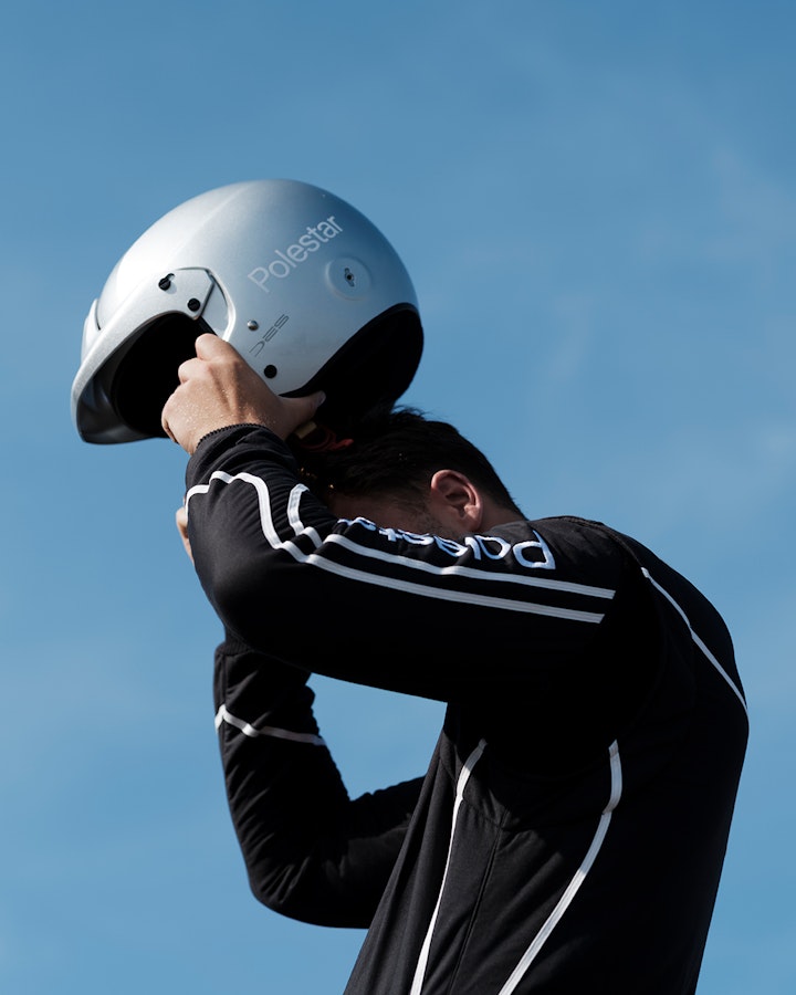 Race driver putting on helmet clear blue sky in the background