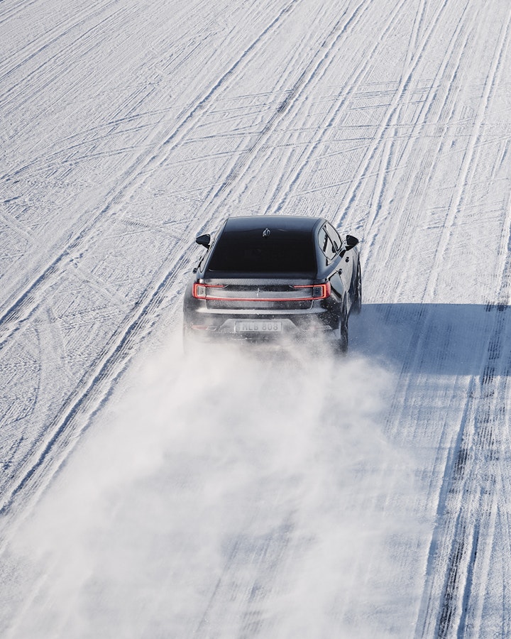 Polestar 2 in black driving in a straight line across the icey lake