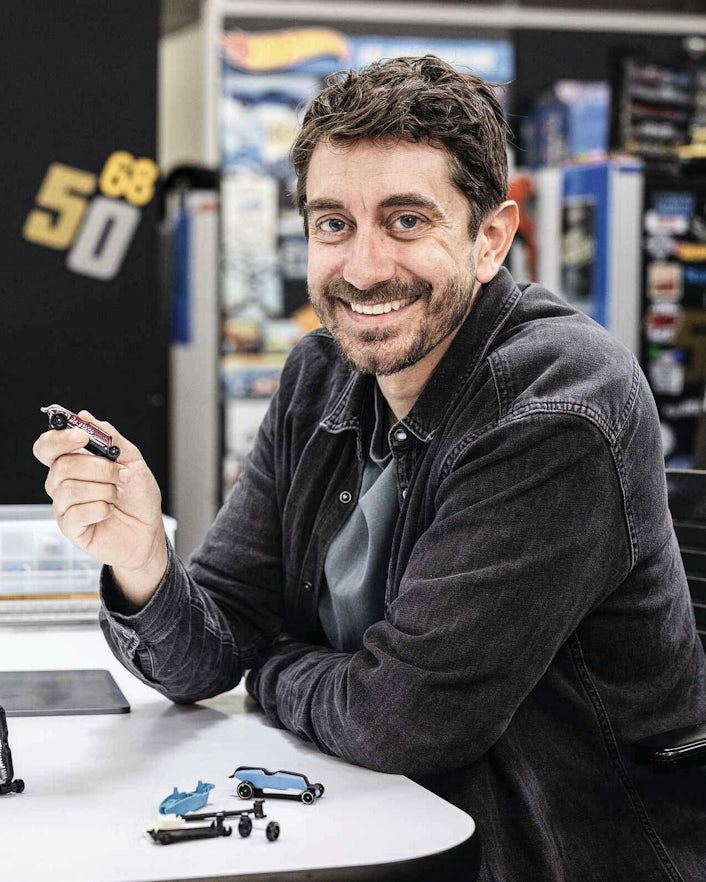 Man sitting at desk holding toy car