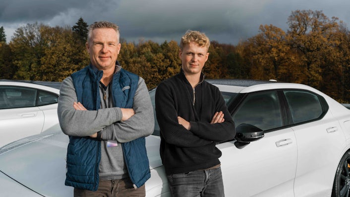 Two peope standing in front of a white Polestar