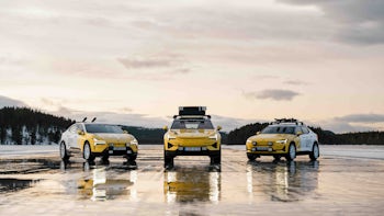 Three white and yellow cars parked on a frozen lake