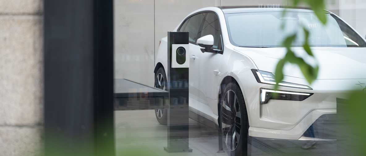 A white Polestar 4 inside a showroom parked next to a charger